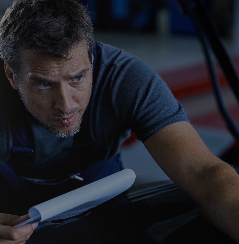 Car mechanic examining vehicle problems while working at auto repair shop.